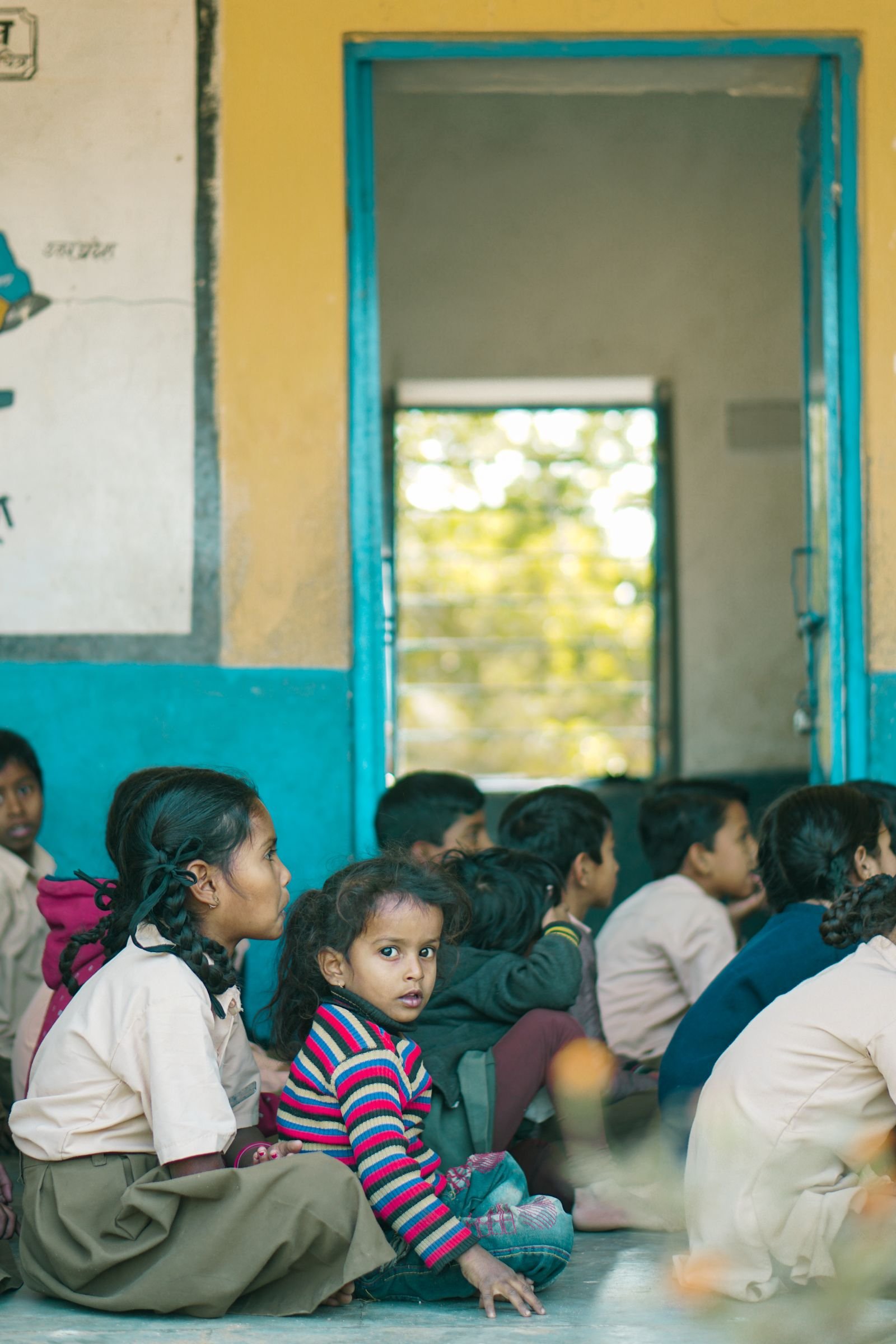 Children seated together in the doorway of a village school.